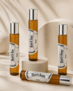 três frascos de perfume portátil feitos de vidro âmbar com tampas prateadas e rótulos brancos redondos na vertical e mais um na horizontal