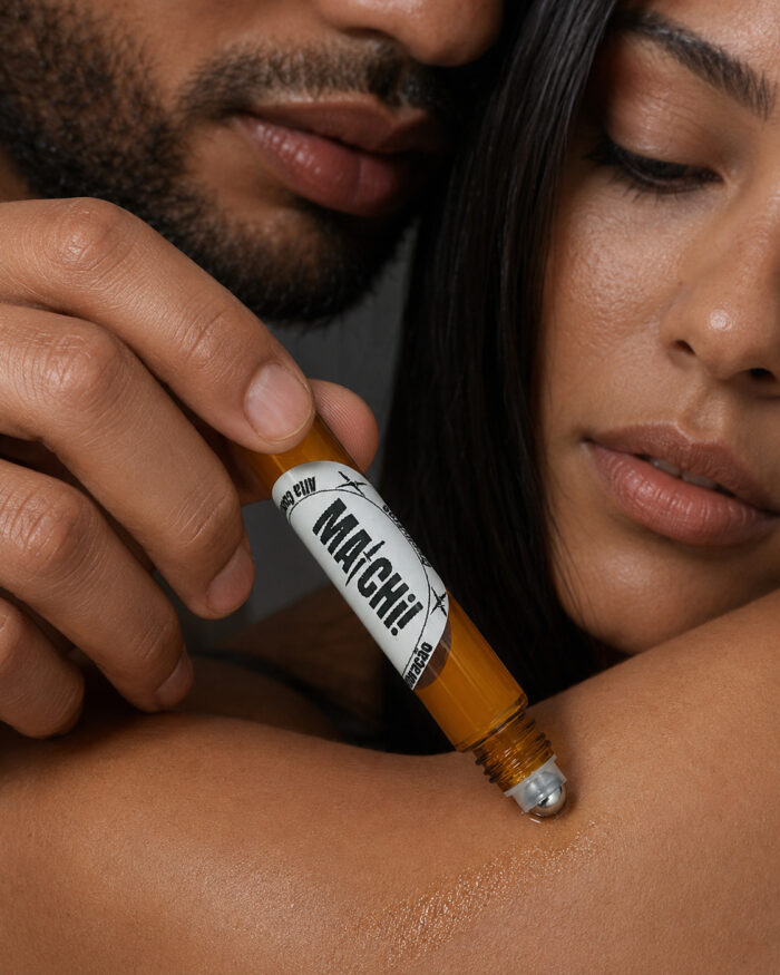 homem com rosto junto ao da mulher aplicando com mão direita perfume com frasco cilíndrico feito de vidro âmbar e ponta de esfera de aço deslizante no cotovelo