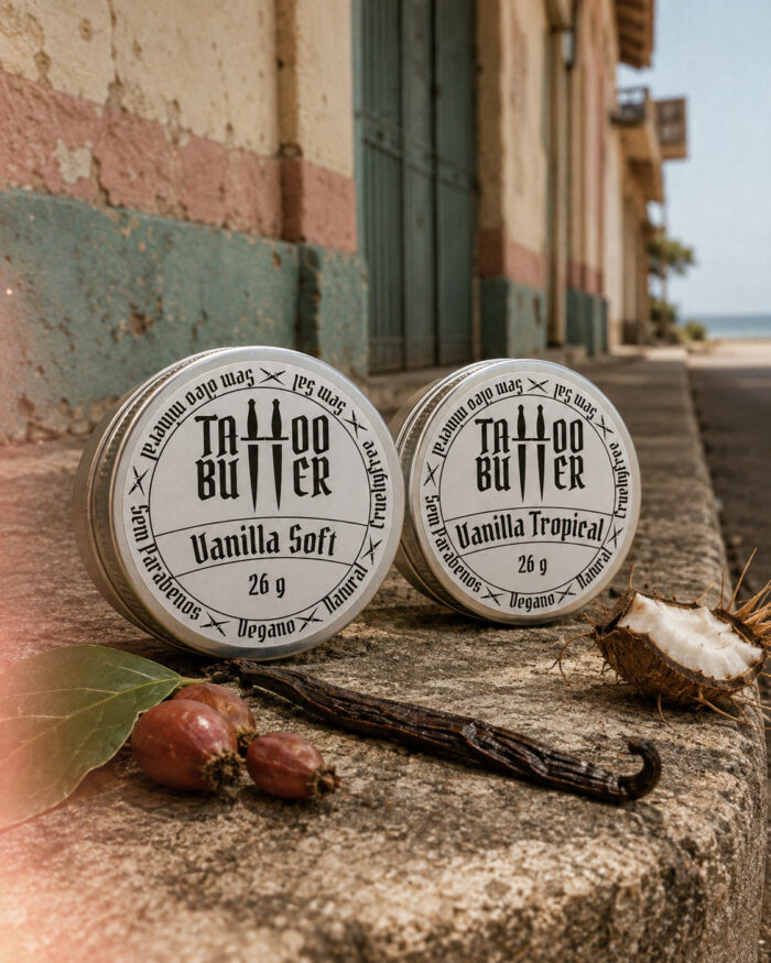 Duas latinhas de alumínio Matchii com rótulos brancos redondos escritos Vanilla Soft e Vanilla Tropical, lado a lado sobre muro rústico, com coco, baunilha, folha e frutos em primeiro plano.